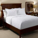 A bed with a 1888 Mills white polyester top sheet and pillows.