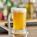 A glass of beer with foam on a counter.