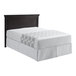 A bed with a white sheet and a gray circles top sheet on a black headboard.