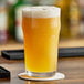 A close up of a glass of True Citrus crystallized orange powder on a coaster.