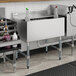 A Regency underbar ice bin machine on a counter with sliding lid open over ice and bottles on a shelf.