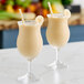 Two glasses of Fresh Blends banana beverage with straws and bananas.