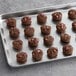 A baking sheet with Otis Spunkmeyer chocolate cookies with pink candy gems on it.