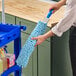 A hand holding a blue Lavex Flex Wand Duster with a chenille sleeve.