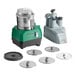 A combination food processor set with a green and black base, stainless steel bowl, continuous feed attachment, and six metal discs.