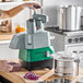 A commercial combination food processor with a stainless steel bowl, continuous feed attachment, and control panel, shown on a kitchen counter.