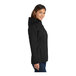 A close-up of a Port Authority women's black parka jacket with a hood and zipper.