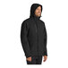 A man wearing a black Port Authority parka jacket with a hood.