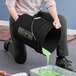 A woman pouring green paint into a black BWAY bucket.