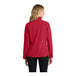 A woman wearing a Port Authority rich red soft shell jacket.