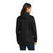 A woman wearing a black Port Authority all-conditions parka jacket.