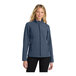A woman wearing a Port Authority navy heather soft shell jacket.