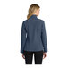 A woman wearing a navy blue Port Authority Core Soft Shell jacket with a zipper and pockets.