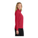 A woman wearing a rich red Port Authority soft shell jacket.