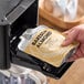 A person using a Numilk commercial plant-based milk machine to fill a bottle with almond milk.
