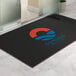 A large rectangular black entrance mat with a colorful logo and text, designed for indoor or outdoor use.