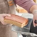 A person cutting a Prime Roots Vegan Hickory Koji-Bacon slab on a counter.