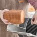 A person cutting a Prime Roots Vegan Classic Smoked Koji-Ham deli chub on a table.
