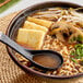 A bowl of Nippon Shokken shoyu ramen soup with noodles and vegetables.