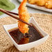 A bowl of Nippon Shokken Wasabi dressing with chopsticks holding a fried shrimp.