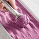 A hand scooping Villa Dolce Ube Purple Yam Gelato with a metal scoop.