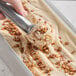 A hand scooping Villa Dolce Maple-Roasted Butter Pecan Gelato into a metal pan.