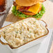 A white dish with a bowl of mashed potatoes and a cheeseburger.