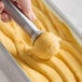 A hand holding a scoop of Villa Dolce passion fruit sorbet.