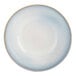 A close-up of a white porcelain serving bowl with beige and blue stripes on the rim.