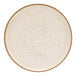 A white Cosy & Trendy stoneware coupe plate with black dots around the rim.