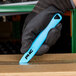 A person in a black glove using a blue Pacific Handy Cutter Dart safety cutter.