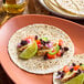 A 6-inch flour tortilla topped with grilled chicken, black beans, diced tomatoes, red onions, jalapeÃ±os, and a lime wedge on a plate.