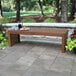 An Outdoor Interiors Eucalyptus bench on a stone patio.