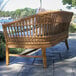 An Outdoor Interiors wicker couch with cushions on a stone patio.