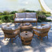 An outdoor patio with an Outdoor Interiors Bohemian Teak and Wicker Sofa and table with a bottle of wine on it.