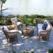 An outdoor patio with a teak and wicker sofa and table with a bottle of wine on it.
