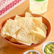 A table with a bowl of Celia's white corn tortilla chips and bowls of salsa and guacamole.