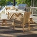 An Outdoor Interiors antique wash eucalyptus and wheat wicker dining armchair next to a table on an outdoor patio.