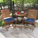 A eucalyptus table and chairs with blue cushions on a patio.