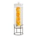 A Cal-Mil glass beverage dispenser with lemons inside on a black wire base.