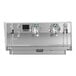 A matte white Victoria Arduino espresso machine with three heads on a counter.