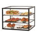A Cal-Mil black metal 3-tier bakery display case with different types of pastries behind glass.