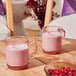 A Duralex Versailles stackable glass mug filled with pink liquid on a table with a glass of pink liquid.