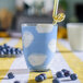 A Duralex blue and white glass filled with blue liquid and blueberries with a straw.