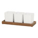 A wooden tray with 3 white square containers inside.