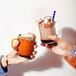 Two hands holding Duralex clear stackable mugs of hot chocolate.