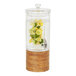 A Cal-Mil round glass beverage dispenser with lemons and limes in it on a rustic pine base.