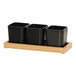 A Cal-Mil oak condiment organizer with three black square containers on a wooden stand.