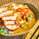 A bowl of Japanese curry with sliced breaded chicken, rice, broccoli, and red pepper, served with S&B Medium Hot Golden Curry Sauce.