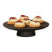 A black Cal-Mil cake pedestal with four small cakes on it.